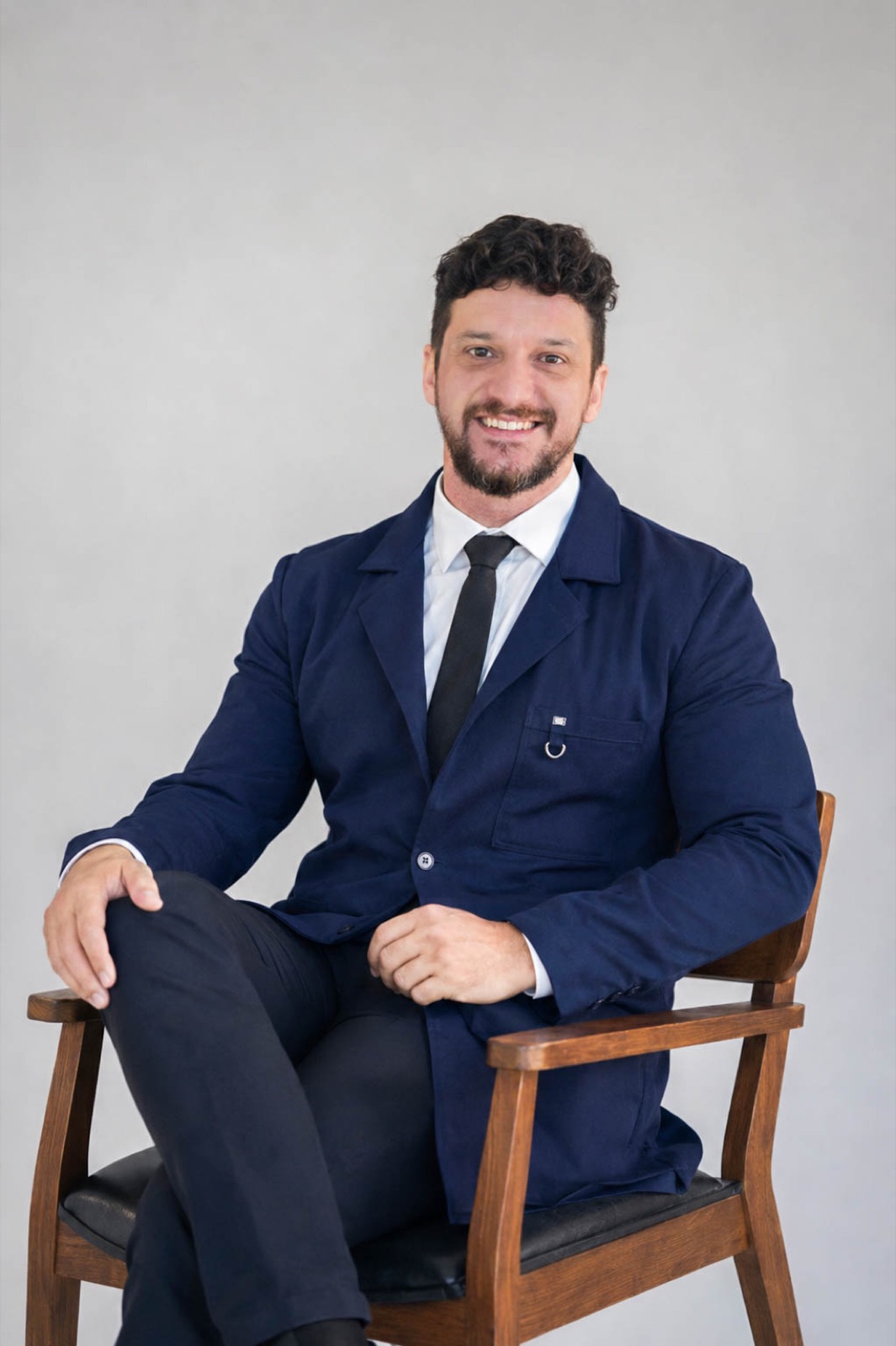 Dr. Bruno Lisboa sentado, sorrindo, de jaleco azul